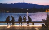 five people sitting near body of water