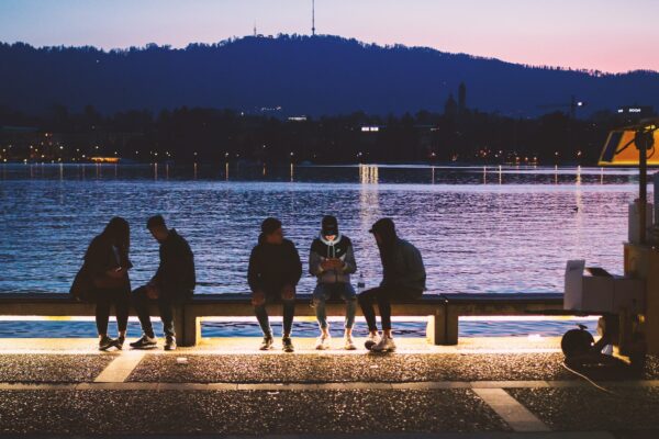 five people sitting near body of water