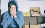 man covering face with both hands while sitting on bench