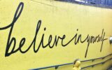 toddler looking at believe in yourself graffiti