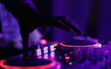 selective focus silhouette photography of man playing red-lighted DJ terminal